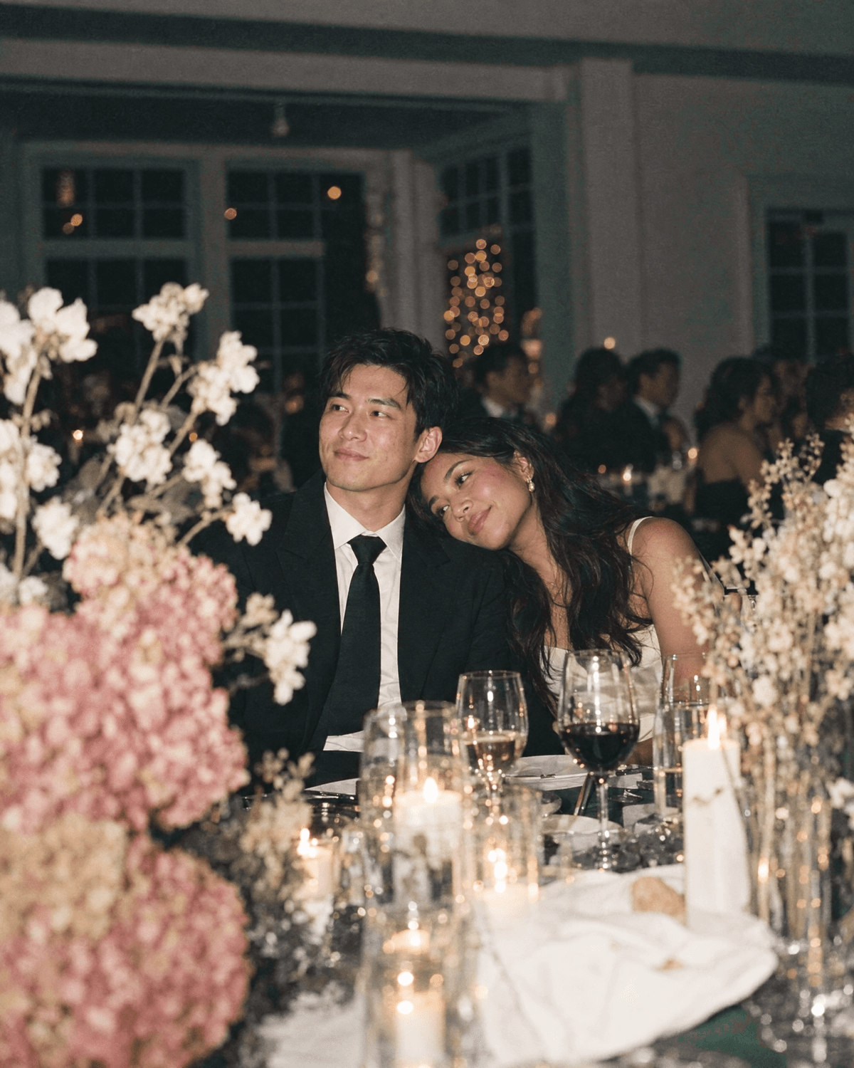 A couple leaning into each other at a candlelit reception table